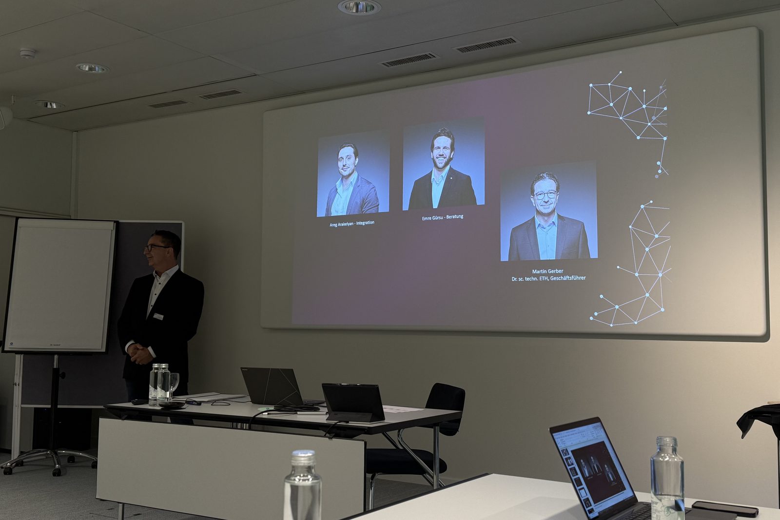 Referent neben der Leinwand mit den Porträts des Referententeams zu Beginn des Workshops